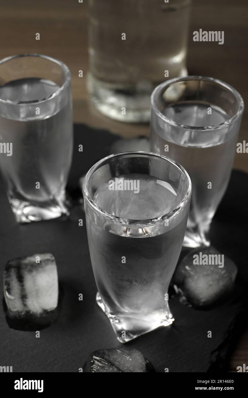 Shot glasses of vodka with ice cubes on table, closeup Stock Photo