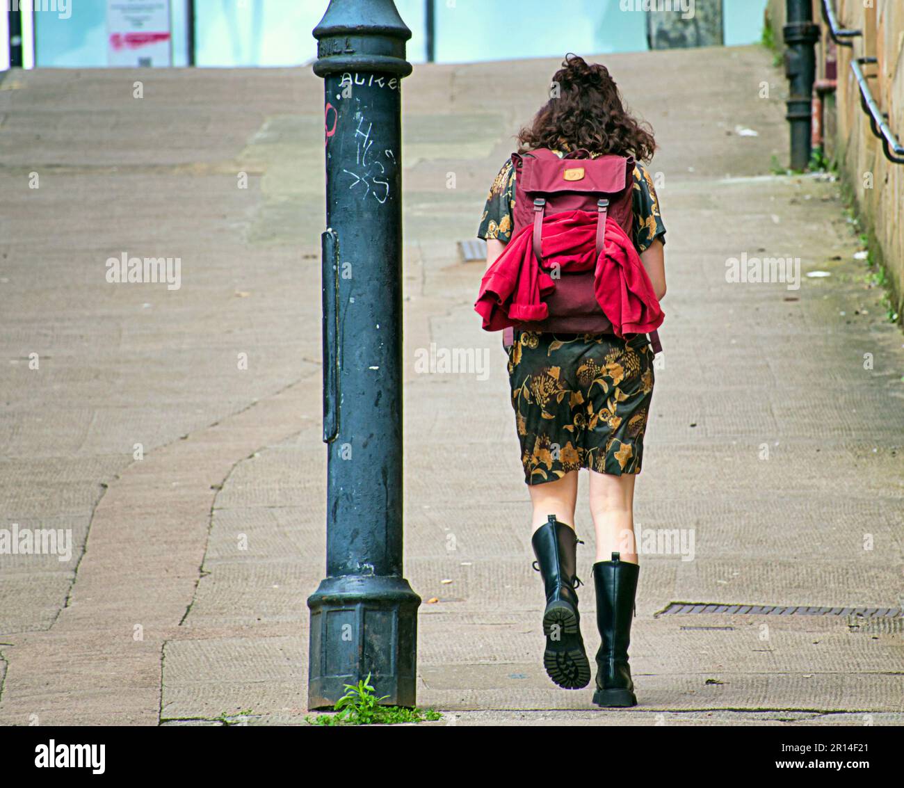 art school girl student with red rucksack climbs steep hill in city centre Stock Photo