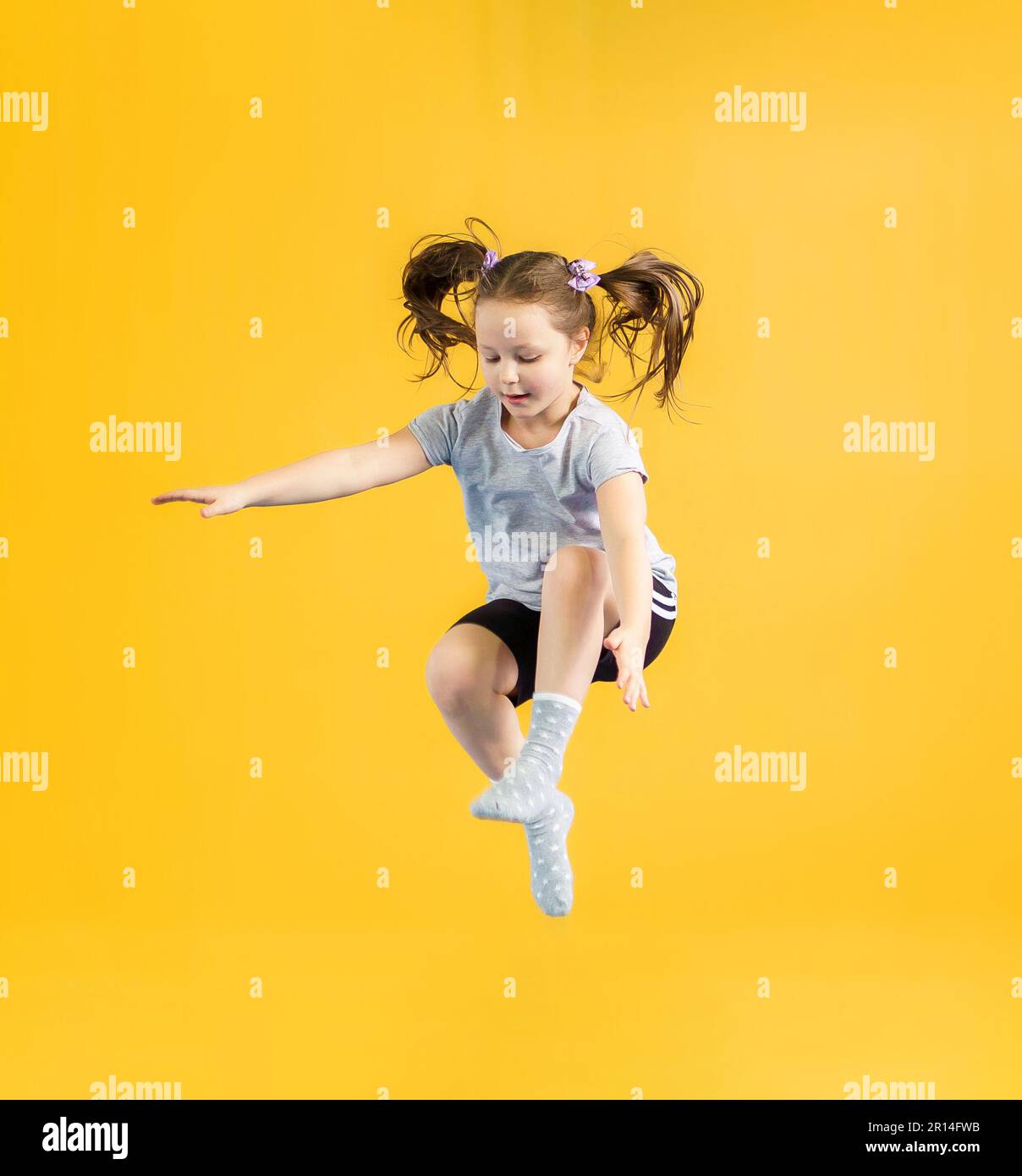 Happy little girl jumping on yellow background Stock Photo - Alamy