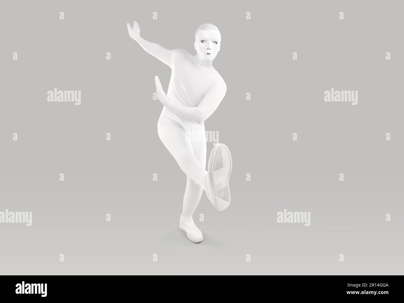 Portrait of man in white mask and bodysuit costume dancing on light