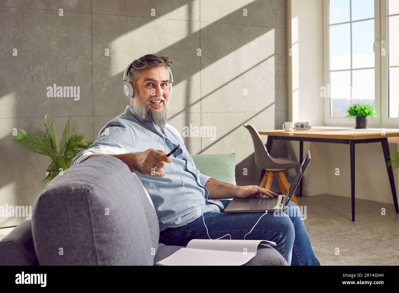 Middle aged man in headphones using laptop at home Stock Photo