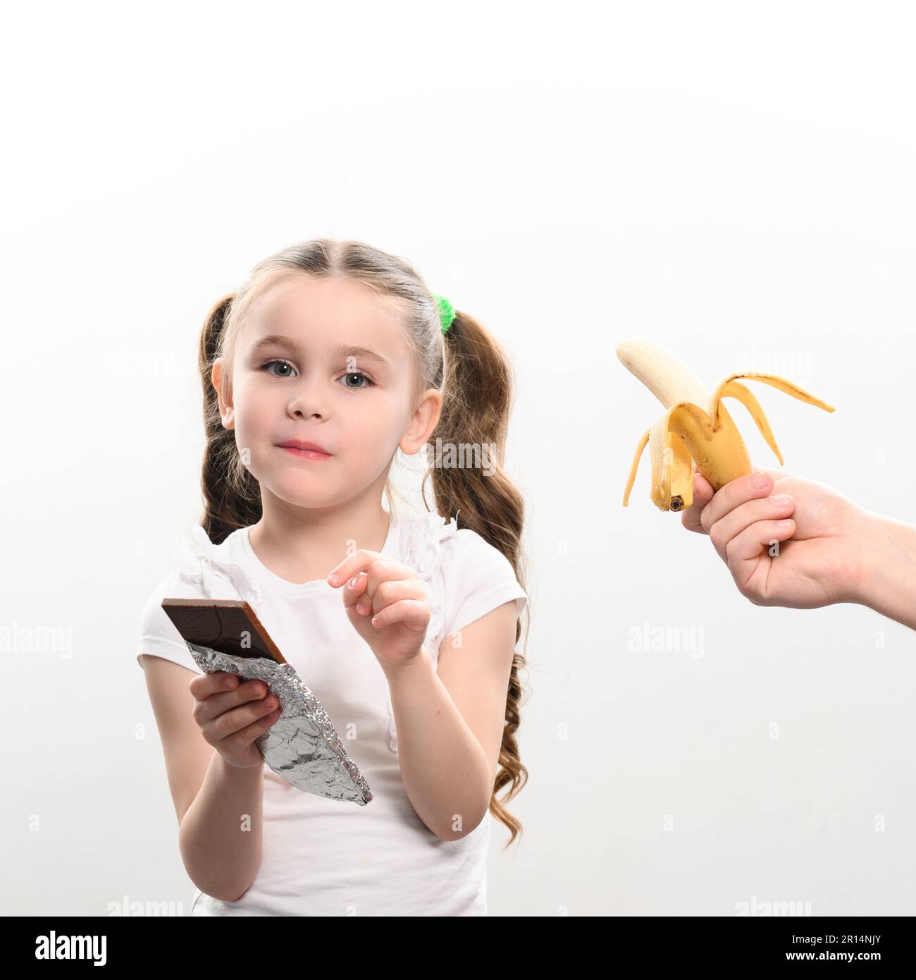 little girl shows with finger that she doesn't want to eat banana and