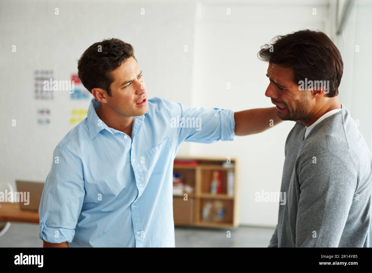 Helping a devastated friend. A young man consoling his sobbing friend. Stock Photo