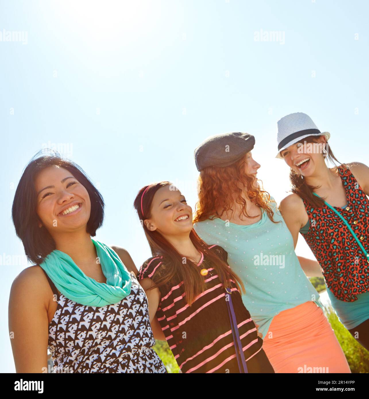 Strolling in the summer sun. Low-angle view of a group of teeange girls walking outside with their arms entwined. Stock Photo