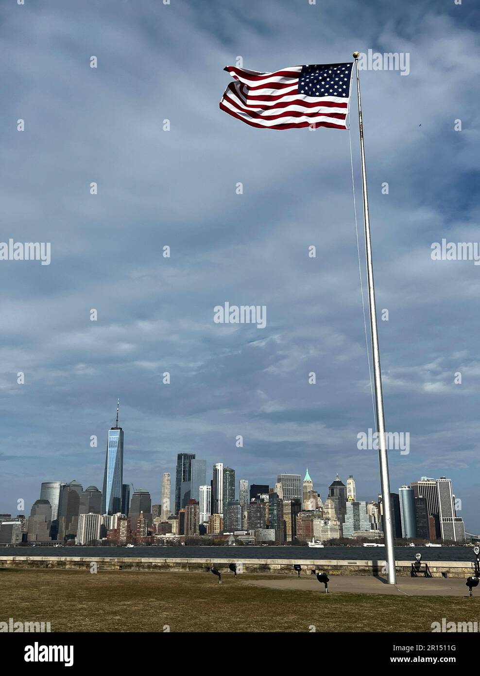 American flag waving on a pole with the skyline of lower Manhattan in the background. Stock Photo