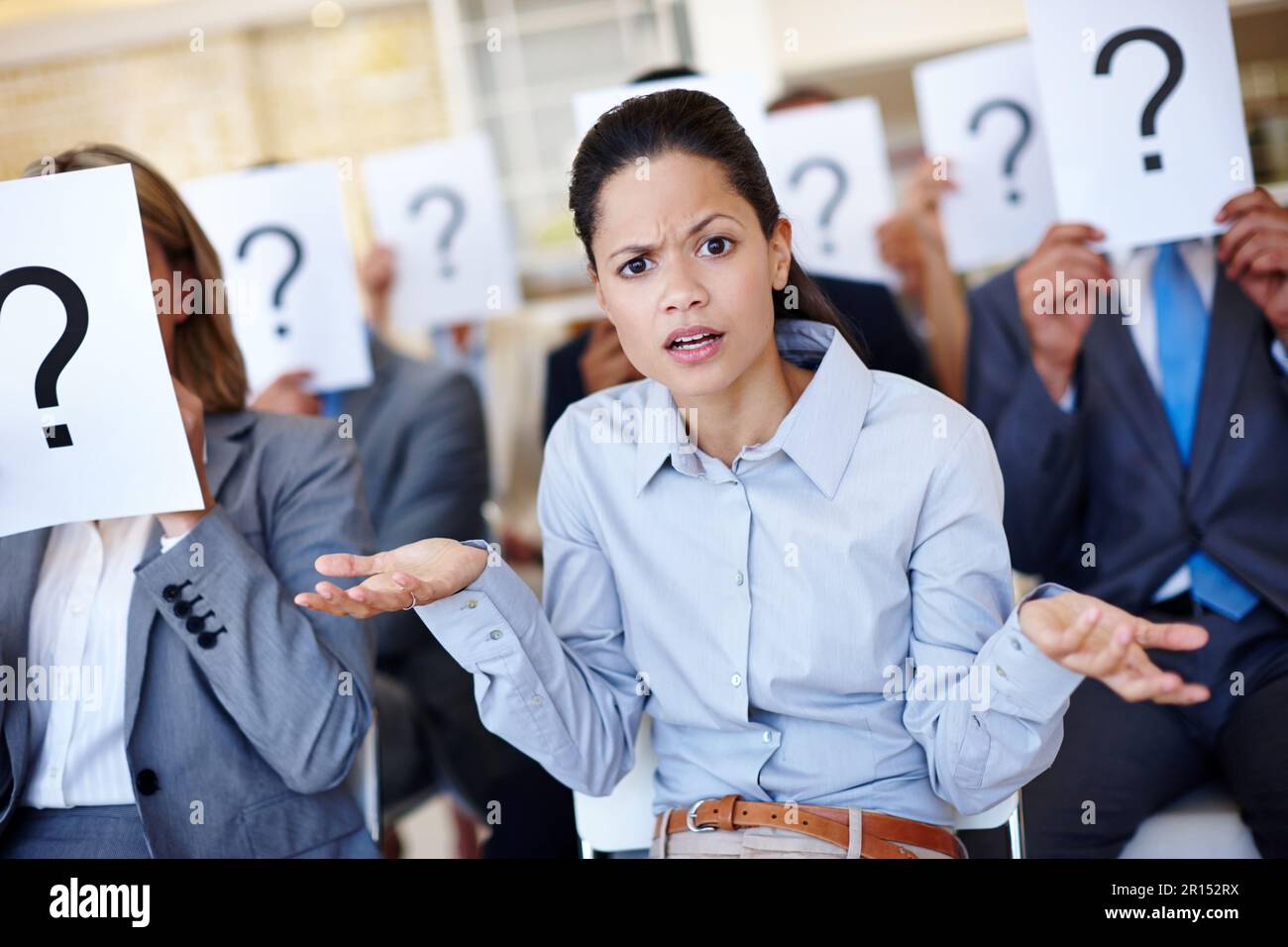 Am I the only one. a group of businesspeople holding up signs with question marks on them during a work presentation while their colleague looks Stock Photo