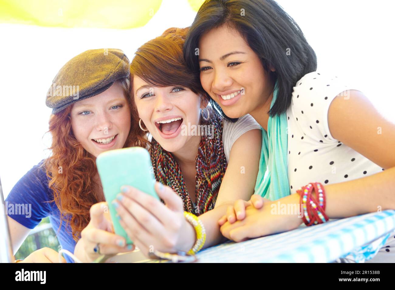 What a funny picture. A group of adolescent girls laughing as they look at something on a smartphone screen. Stock Photo