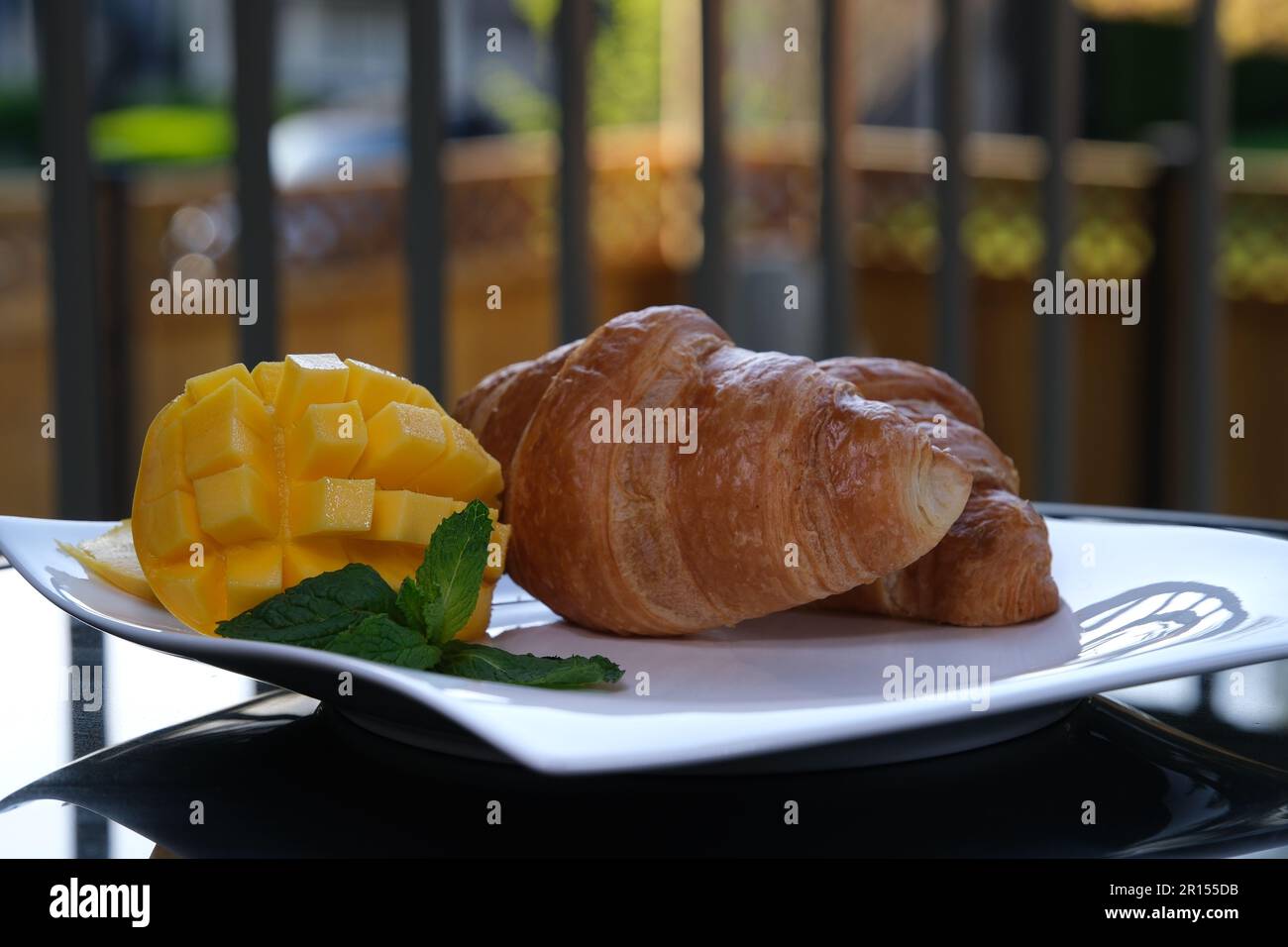 watering croissant with liquid caramel on white plate mango mint leaves