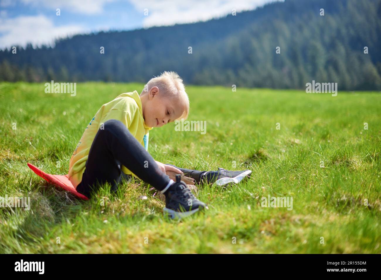 Fun teenager sits on hillside. Boy resting in mountains. School boy