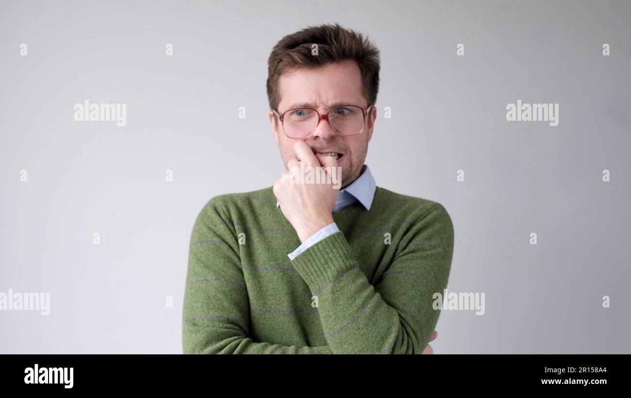 A European young man is nervous and biting his nails. Stock Photo