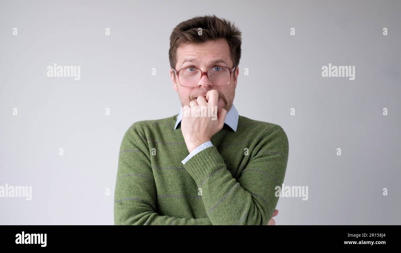 A European young man is nervous and biting his nails. Stock Photo