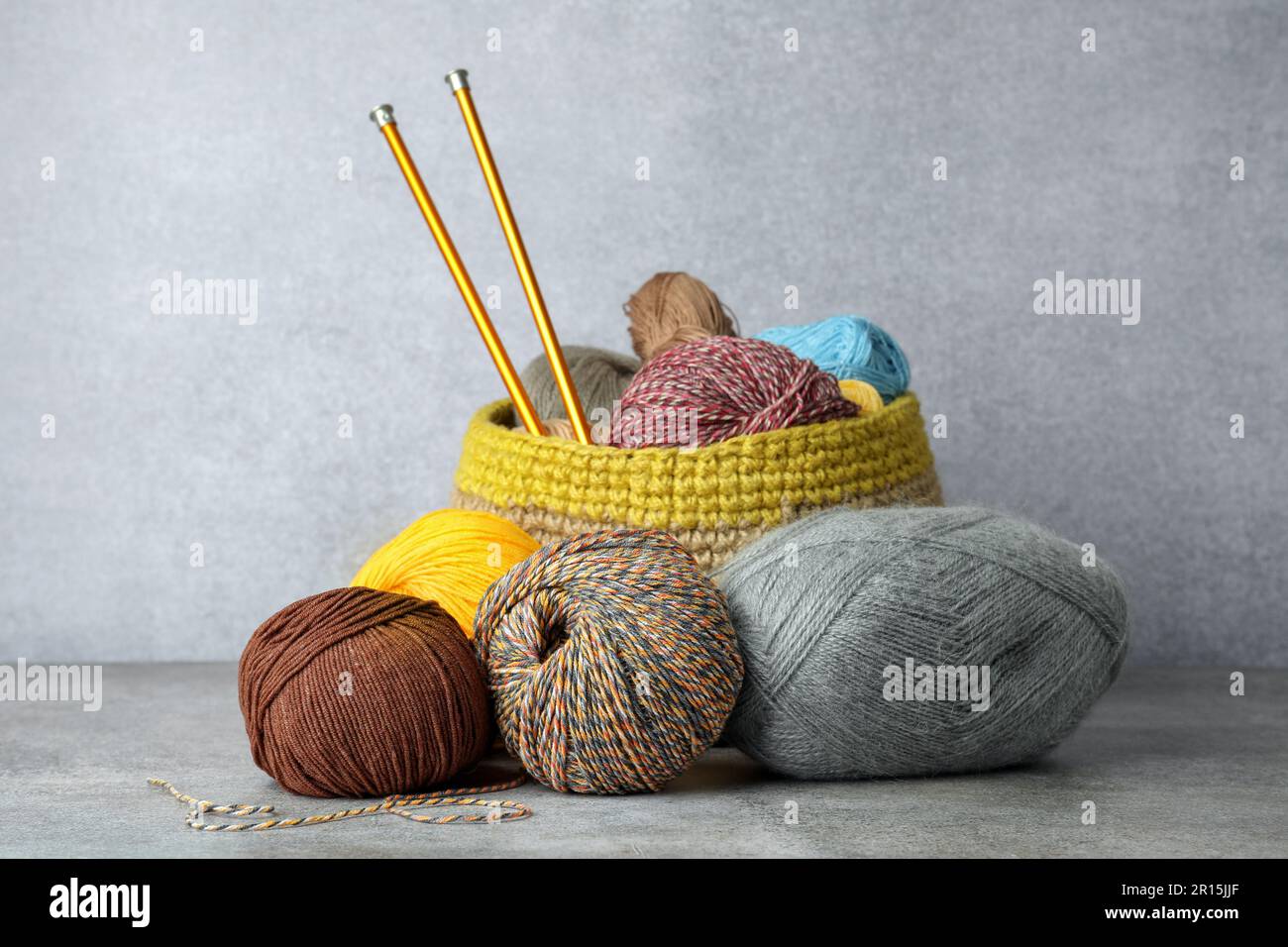 Soft woolen yarns and knitting needles on grey table Stock Photo