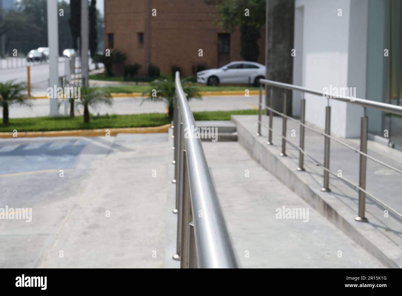 Concrete ramp with metal handrail near building outdoors, closeup Stock