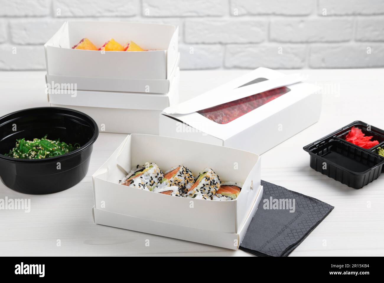 https://c8.alamy.com/comp/2R15KB4/food-delivery-paper-boxes-with-delicious-sushi-rolls-on-white-wooden-table-2R15KB4.jpg