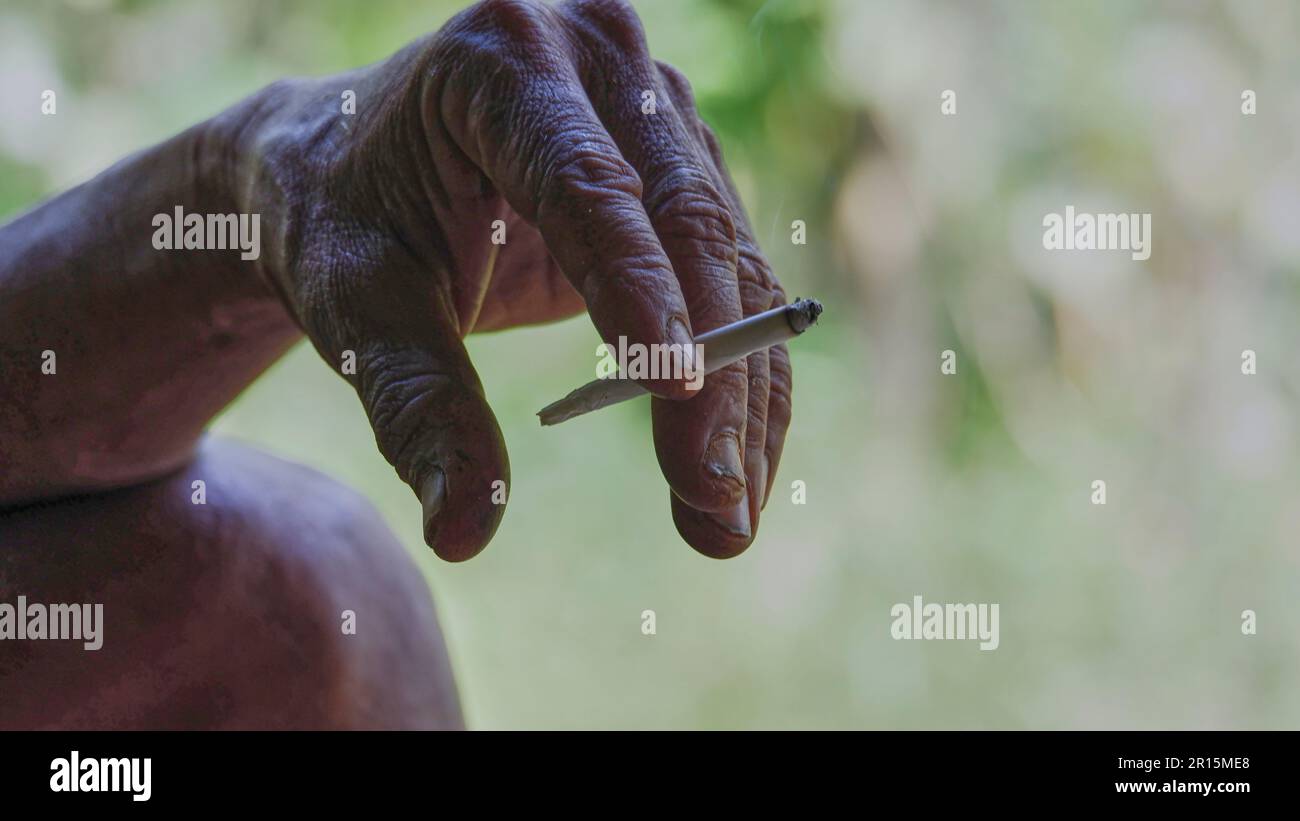 A hand holding a cigarette between the index and middle fingers Stock Photo 