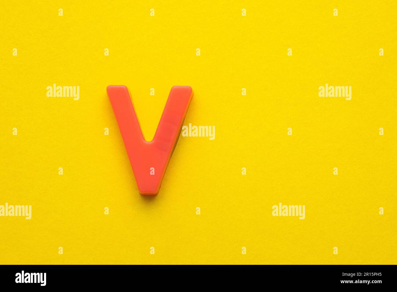 Alphabet letter V - Peach colored plastic piece on yellow foamy ...