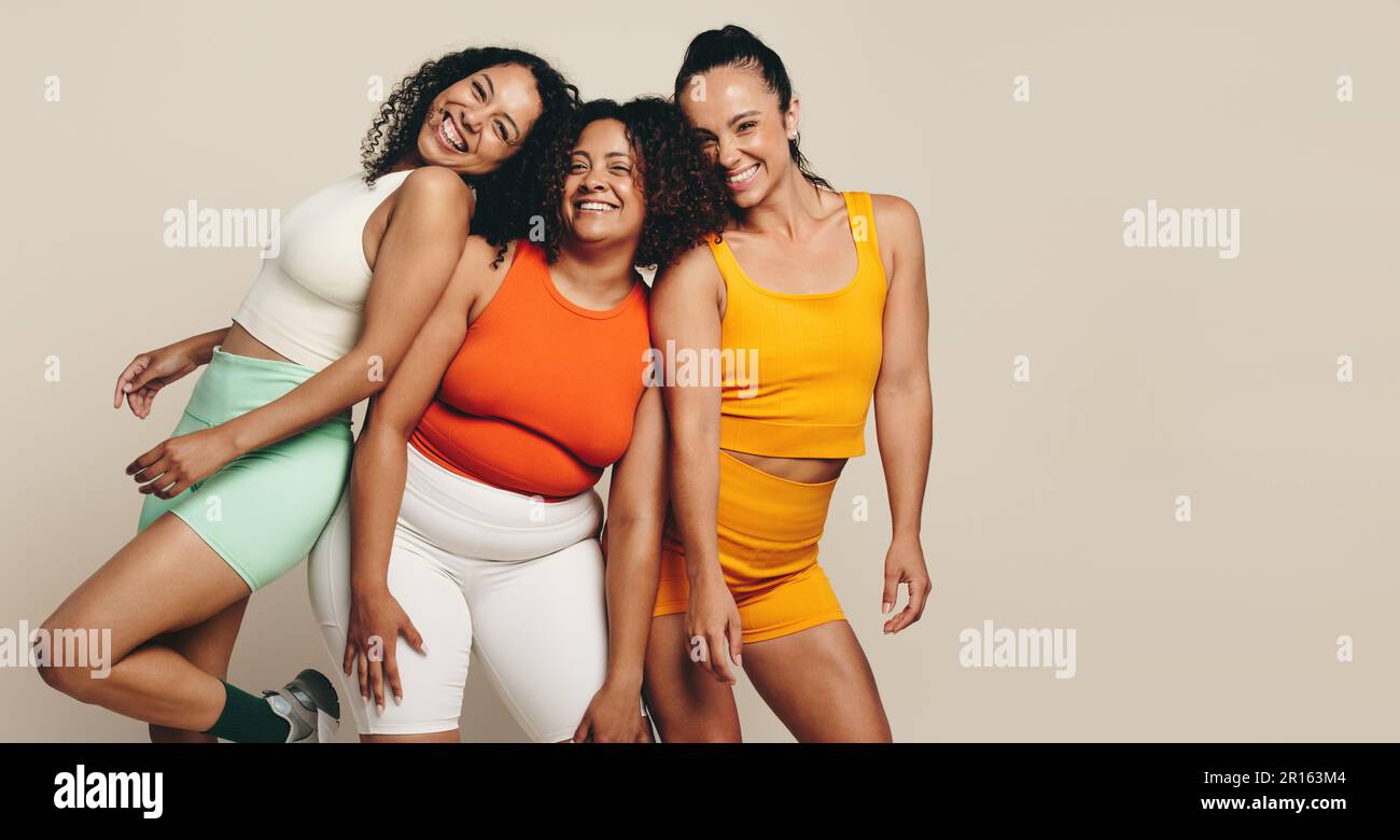Female athletes smiling at the camera as they stand together in a studio,  wearing fitness clothing. Group of young sports women expressing their love  Stock Photo - Alamy