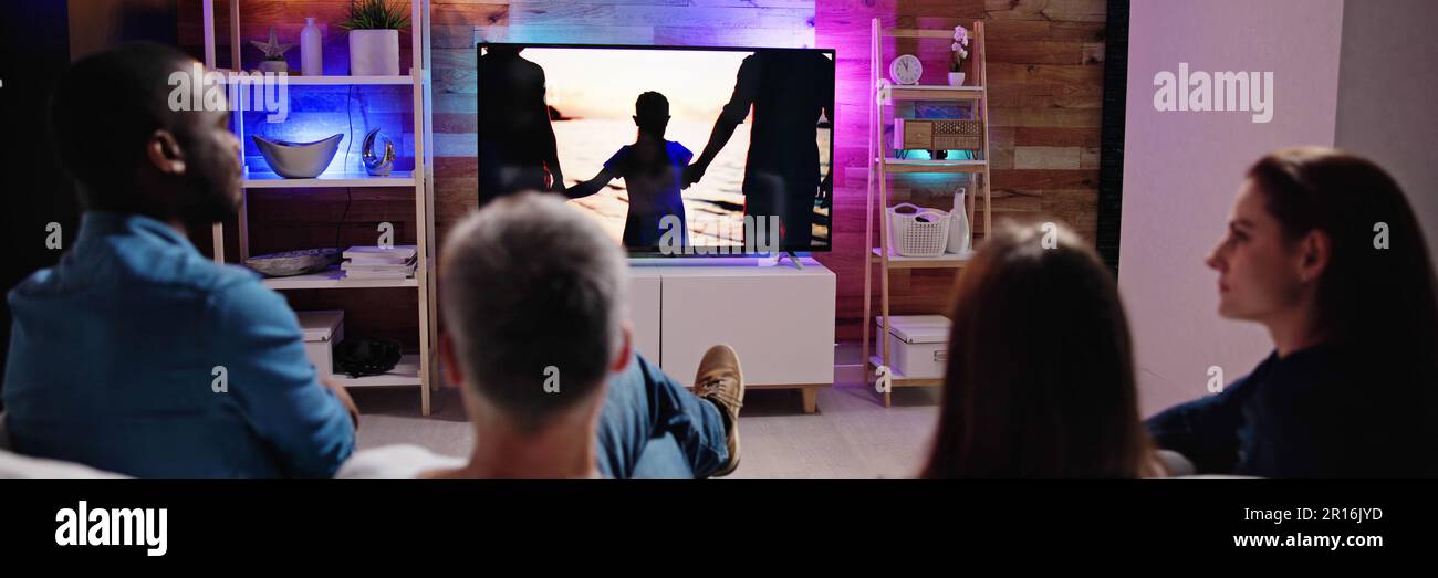 Couples Watching TV At Night. Television Screen Stock Photo