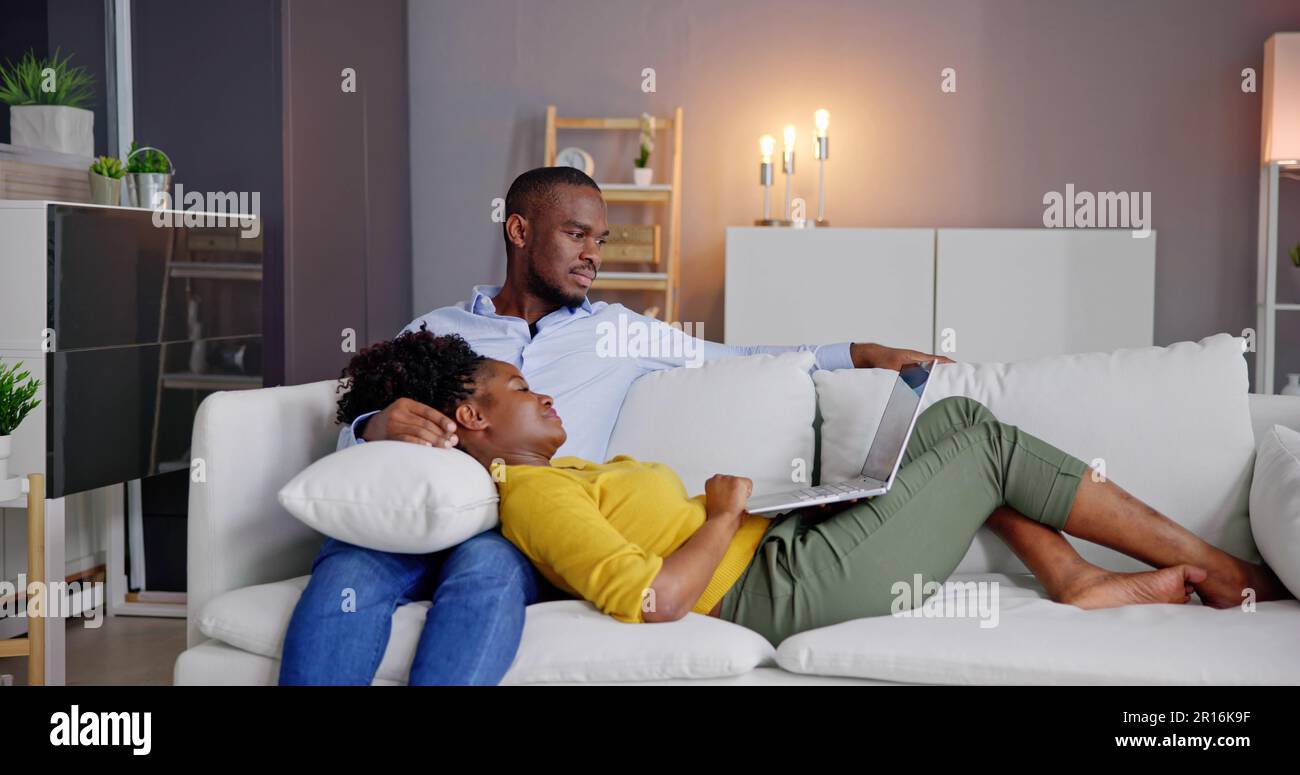 Young Couple Using Laptop On Couch At Home Stock Photo