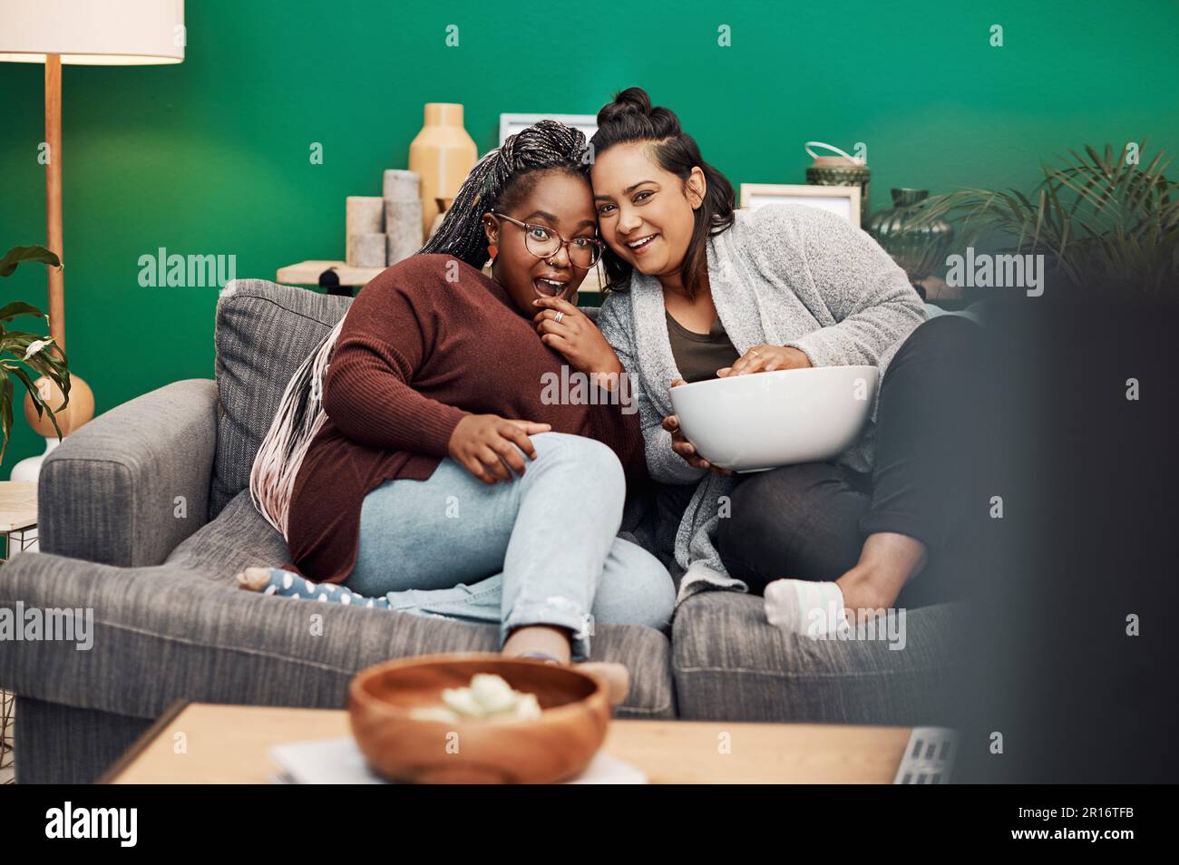 Girl friends, shocking movie and home living room laughing on a couch with a happy smile. Tv, relax and women together in a lounge with a female Stock Photo