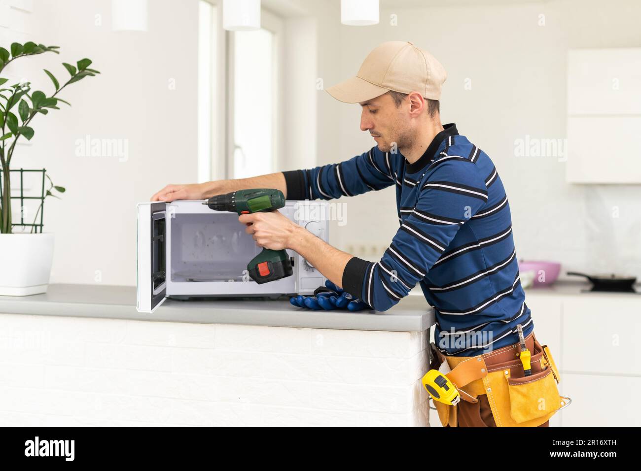 man repairing microwave. a worker repairs a microwave oven. Stock Photo