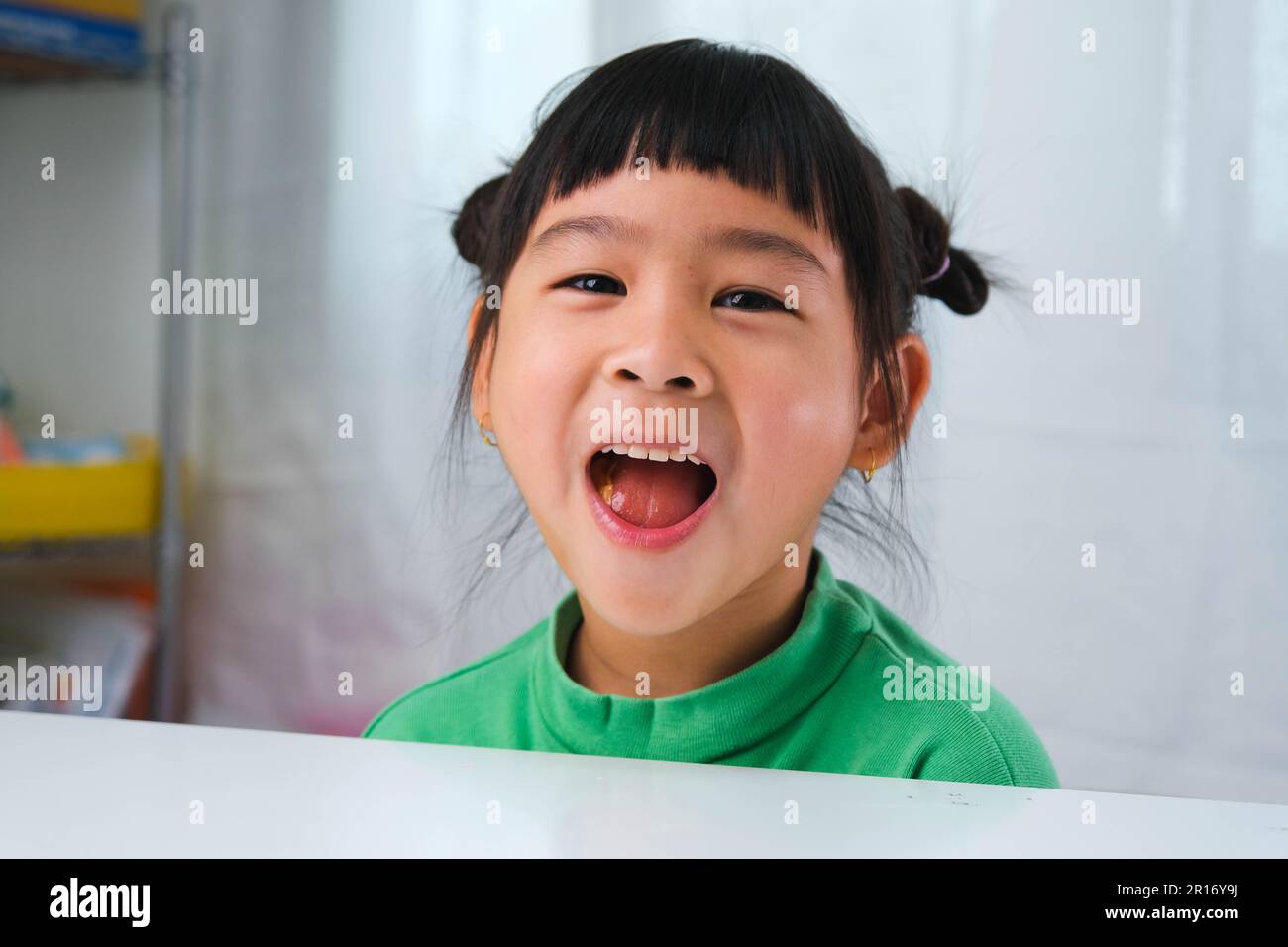 Happy cute little girl eating gelatin candy. Funny kid with chewing gum