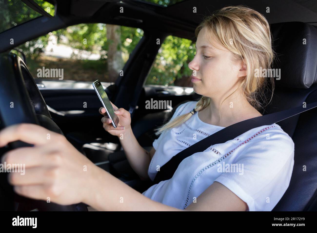 woman reading text while driving her car Stock Photo