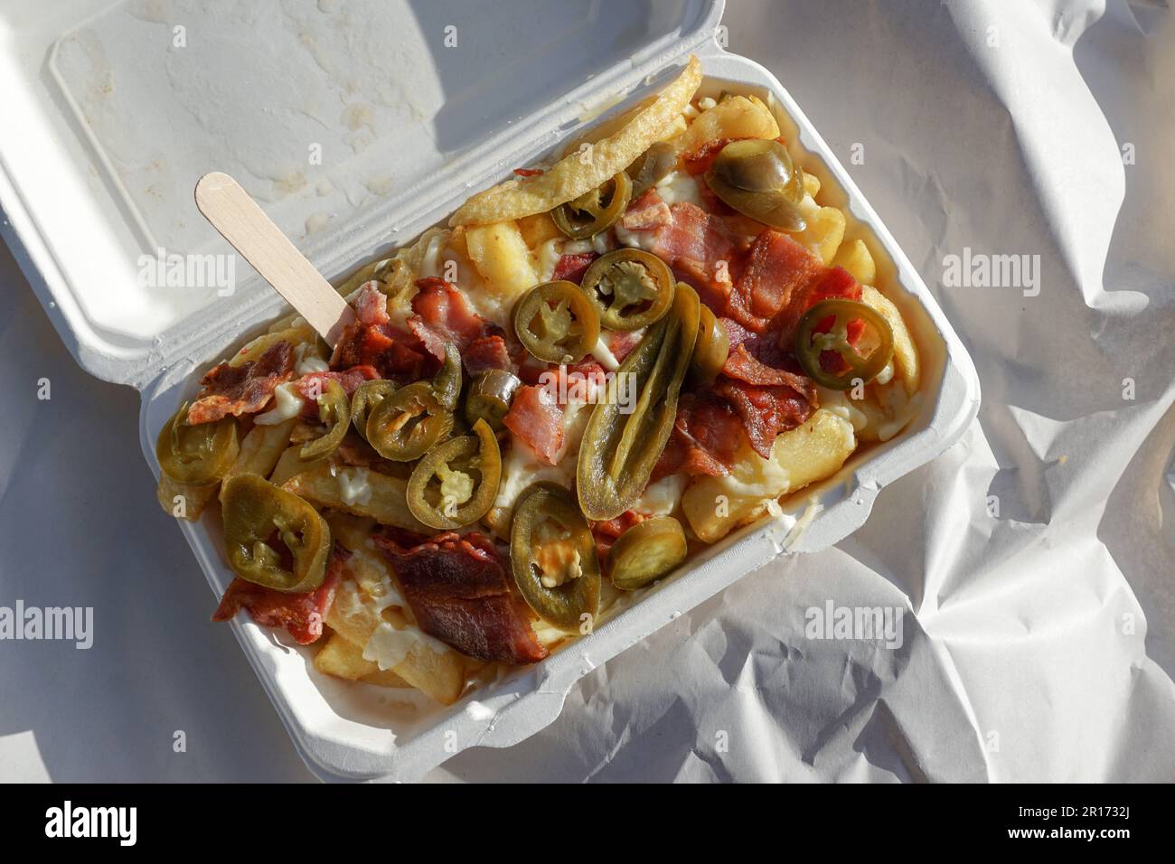 a tray of dirty fries. takeaway portion of chips with jalapenos, bacon and cheese Stock Photo