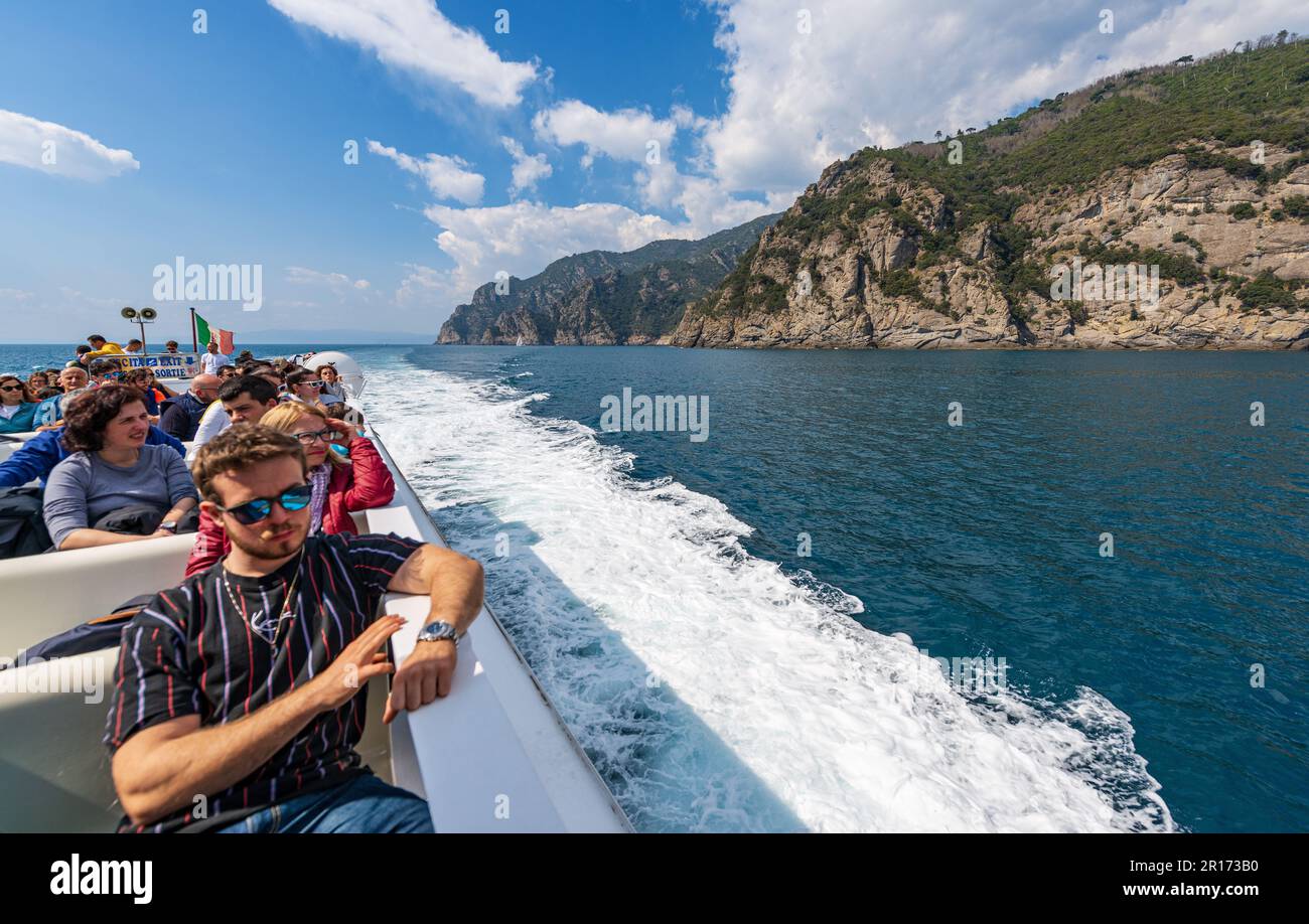 Ferry with tourists in motion from San Fruttuoso to Portofino, tourist resorts in Genoa Province, Liguria, Italy, Europe. Rocky coastline and sea. Stock Photo