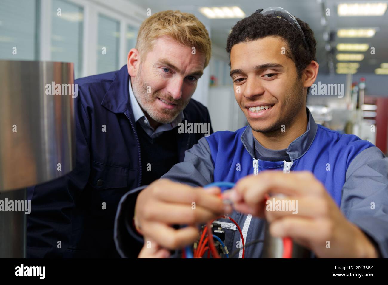 factory worker teaching new employee how to work with wires Stock Photo Alamy