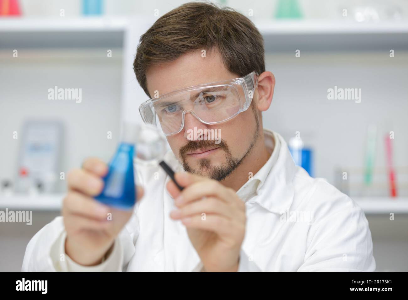 scientist pipetting blue liquid into test tubes Stock Photo - Alamy