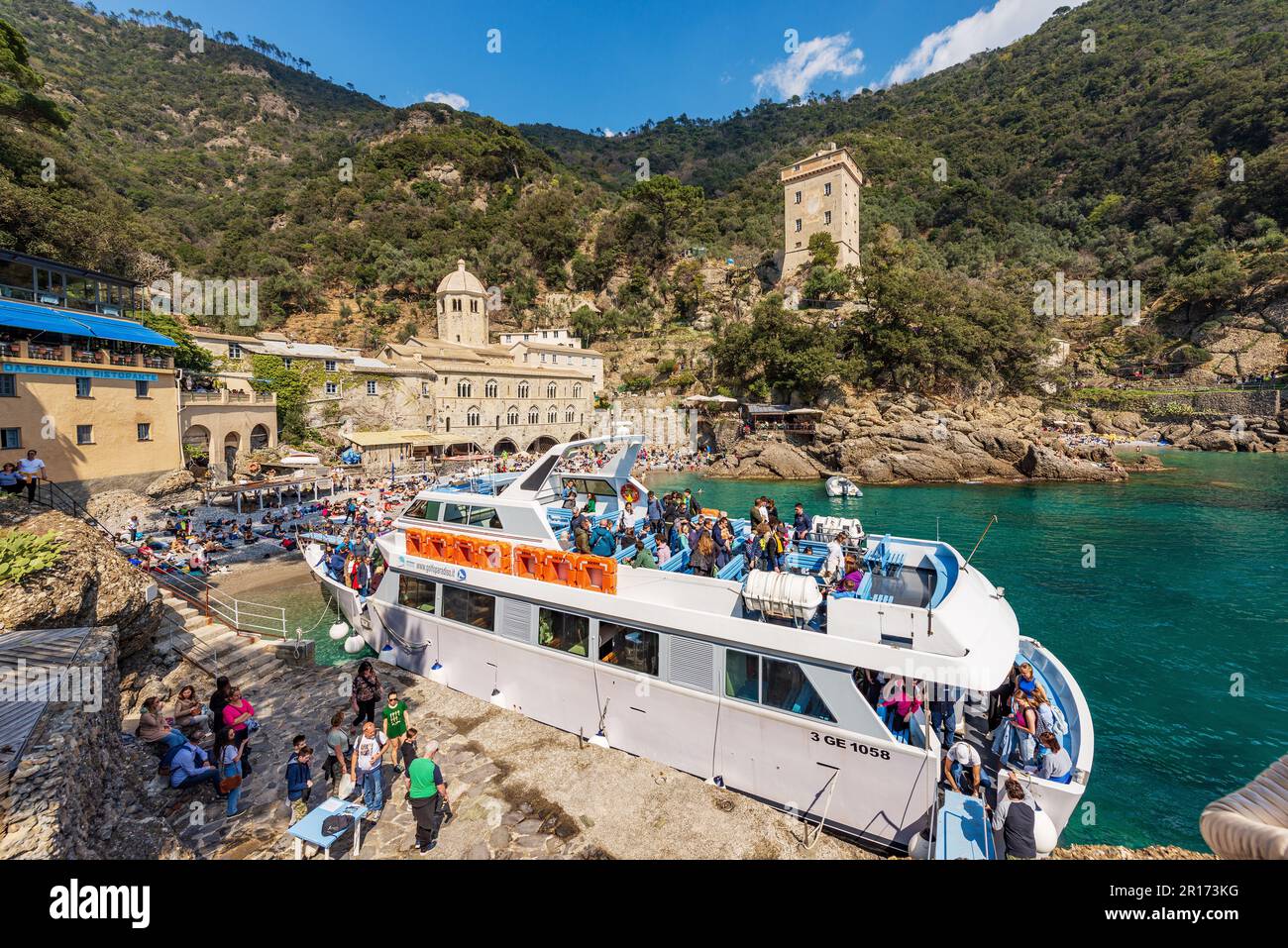 Ancient San Fruttuoso Abbey, X-XI century. Beach and ferry crowded with tourists near Portofino and Camogli, Genoa province, Liguria, Italy, Europe. Stock Photo