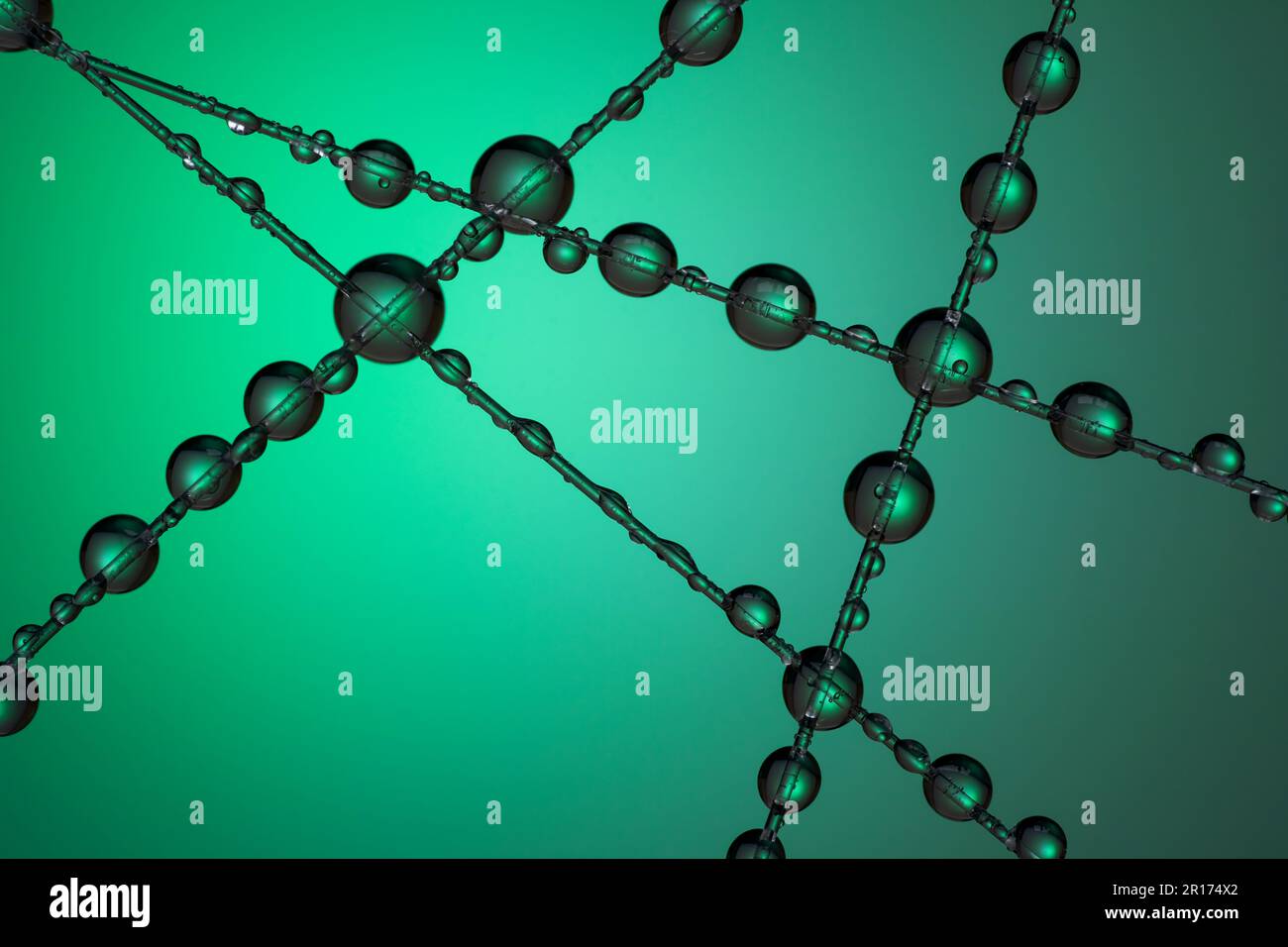 A number of water droplets clinging to a fishing line against a green background Stock Photo