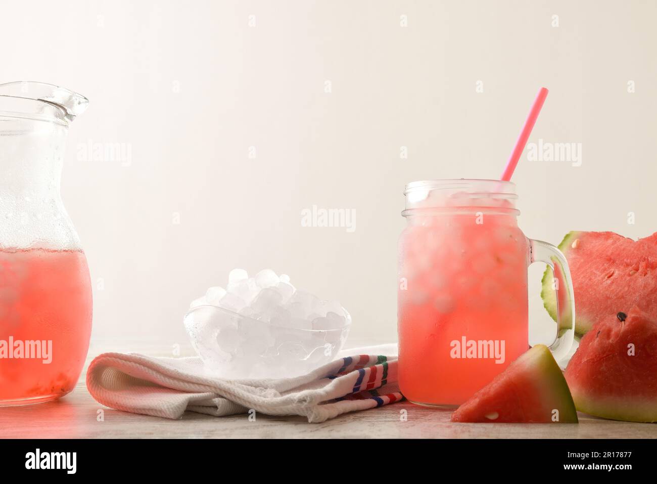 Freshly prepared watermelon drink with crushed ice on table with cut fruit, crushed ice and pitcher. Front view. Horizontal composition. Stock Photo