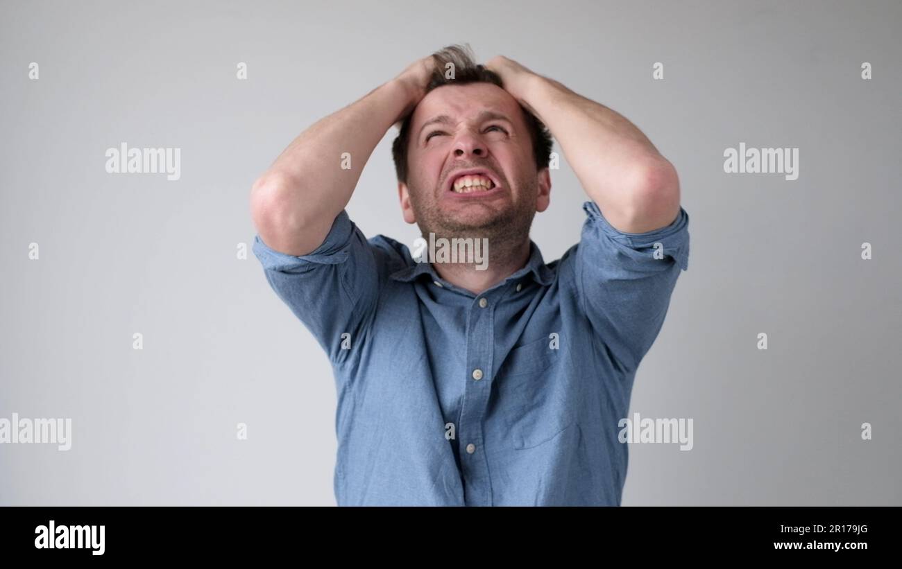 European young man is tearing his hair in despair upon hearing bad news. Stock Photo