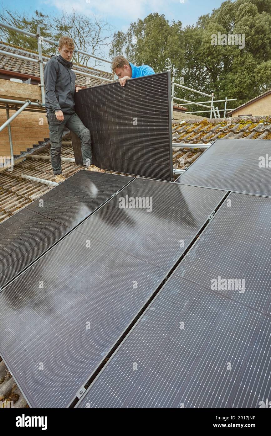 Photovoltaic solar panels being fitted to a residental roof in England