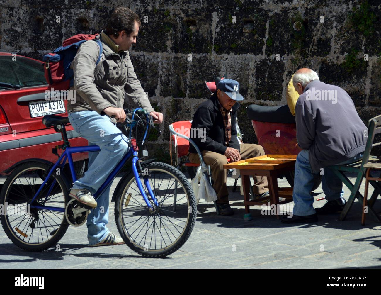 Greece, Island of Rhodes:  a game of backgammon under the city walls, with interested spectator. Stock Photo