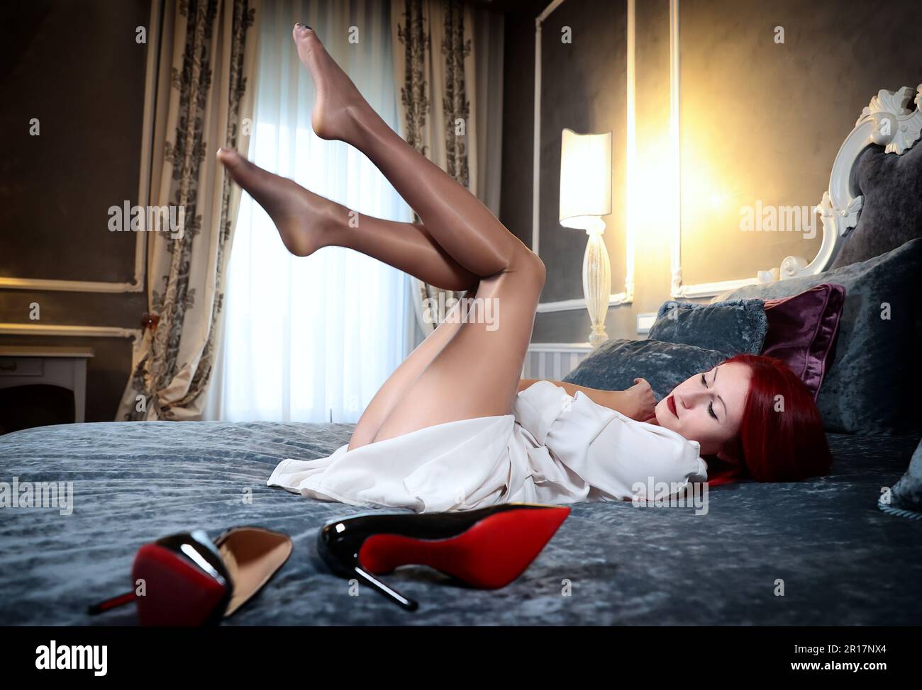 A red-haired girl is wearing shiny nude tights Stock Photo