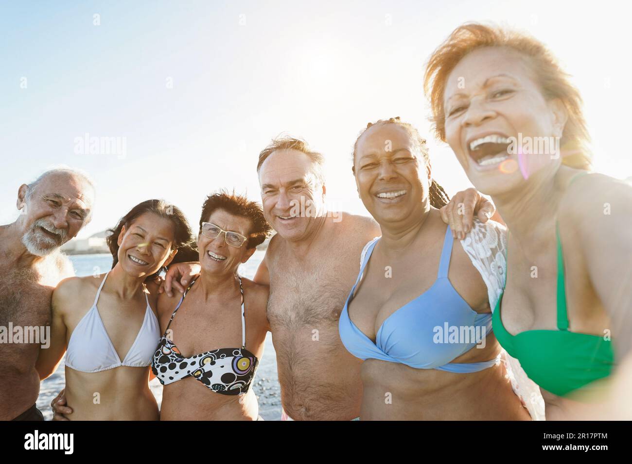 Multiracial senior people taking selfie on the beach during summer vacation - Joyful elderly lifestyle concept, travel and multiracial concept - main Stock Photo