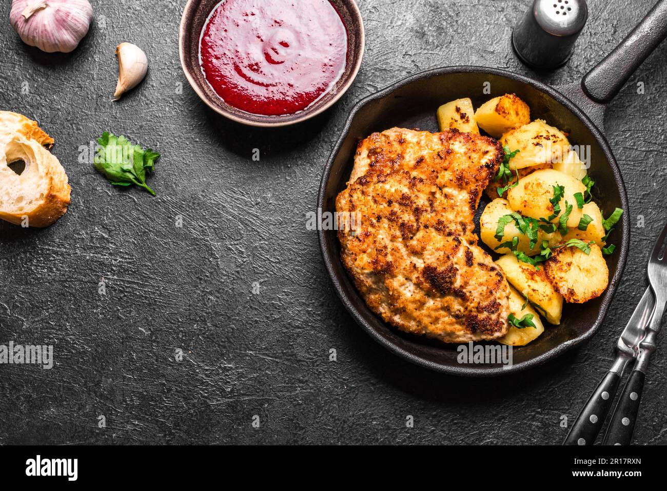German schnitzel with roasted potatoes and cranberry sauce on black