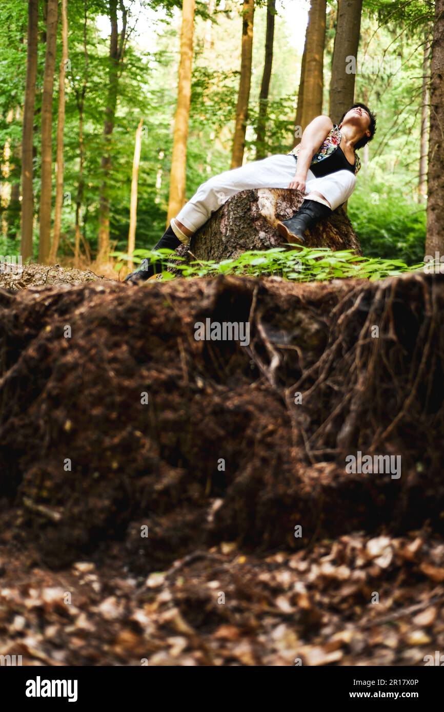 dancer moves on log above earth and roots in german forrest Stock Photo