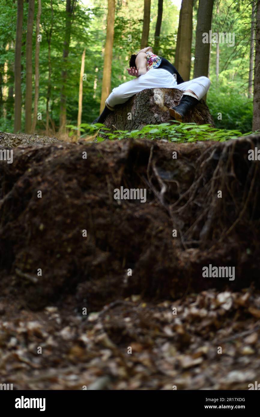 Person opens chest to sky on tree stump above earth in forrest Stock Photo