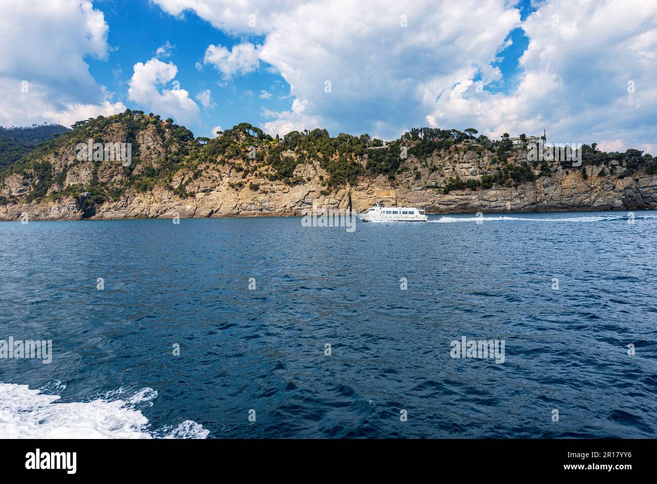 Ferry with tourists in motion from Portofino to San Fruttuoso bay, tourist resorts in Genoa Province, Liguria, Italy, Europe. Rocky coastline and Medi Stock Photo