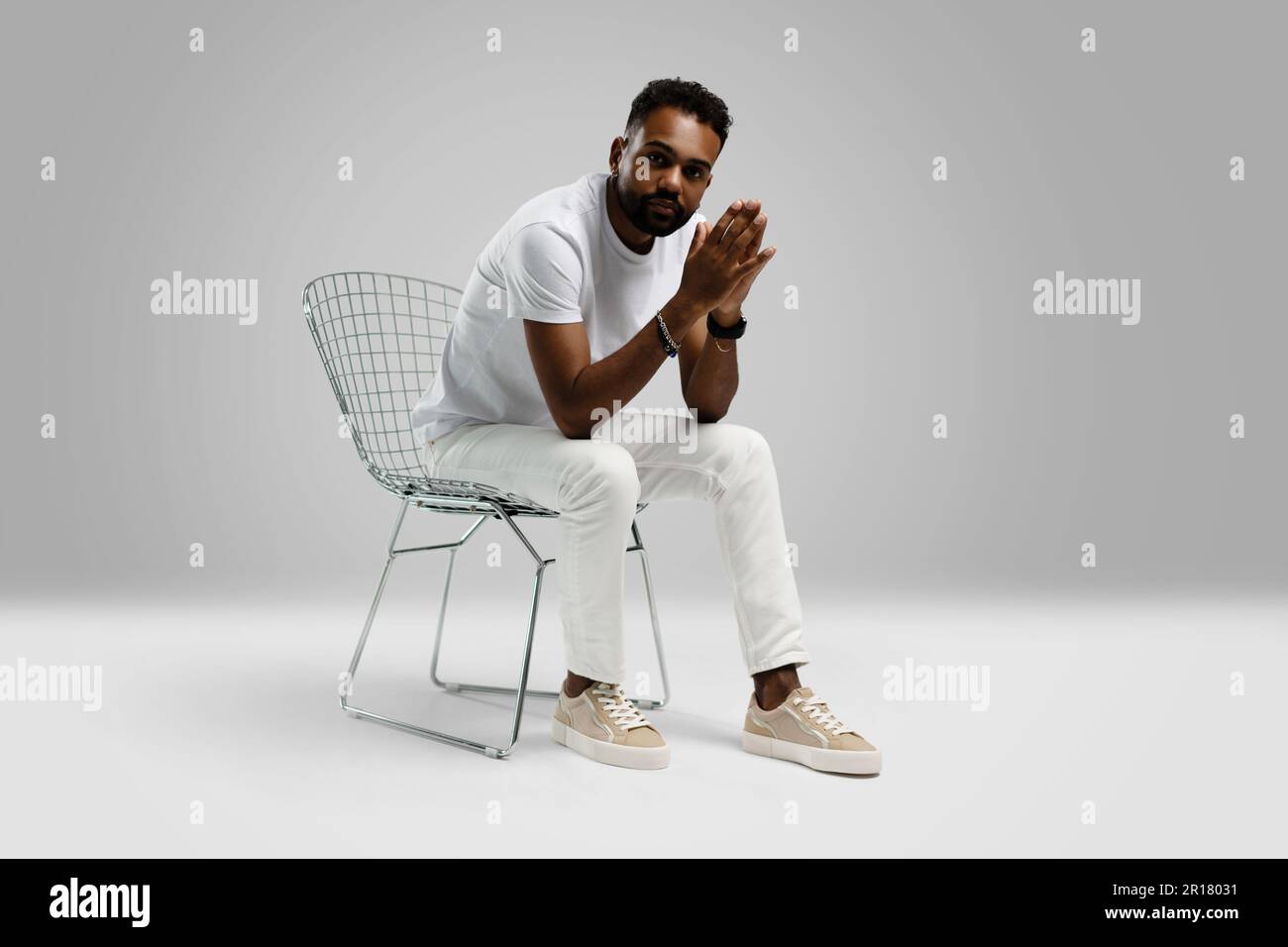Handsome young african american guy sitting on stool, posing in studio - isolated. Stock Photo