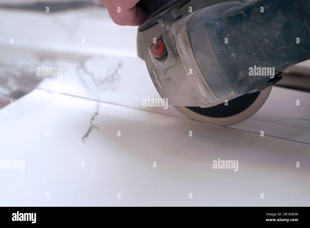 A construction worker saws ceramic tiles using an angle grinder Stock Photo