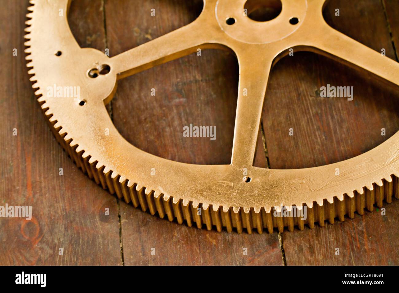 Clock gear, gold and wheel cog on a wood table with golden machinery and gears. Metal, closeup