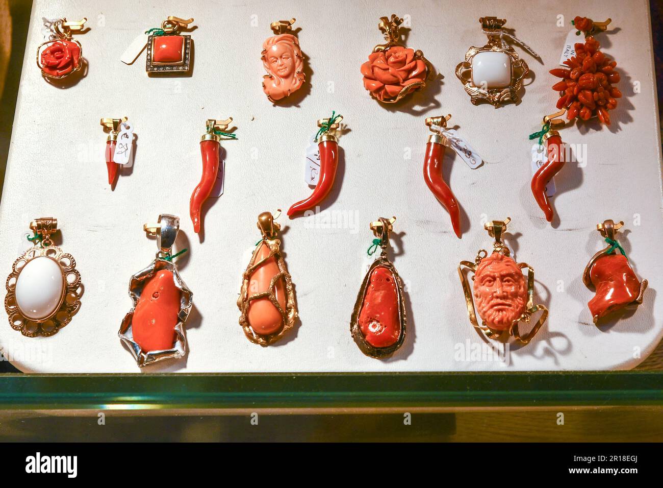 Close-up of a shop window of a jewelry store with coral and gold pendants and lucky horns on a white display, Venice, Veneto, Italy Stock Photo
