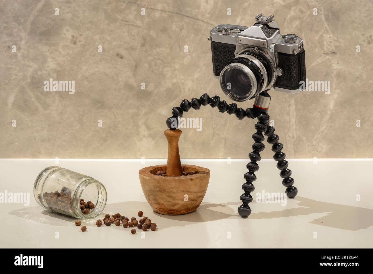 A photo of old analog film camera grinding spices with a wooden hand spice grinder Stock Photo