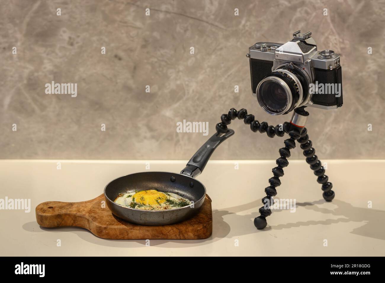 A photo of an old film SLR camera cocking a fried egg Stock Photo