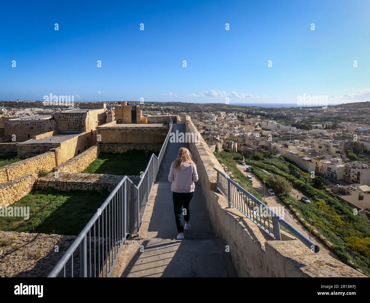 Rabat, Gozo, Malta - April 18, 2023: Woman walking on fortified walls of historical citadel ruins. Stock Photo